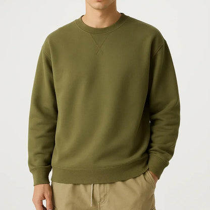 Man wearing an olive green sweatshirt and beige pants on a white background