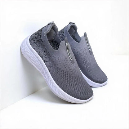 Gray slip-on sneakers with white soles on a light gray background